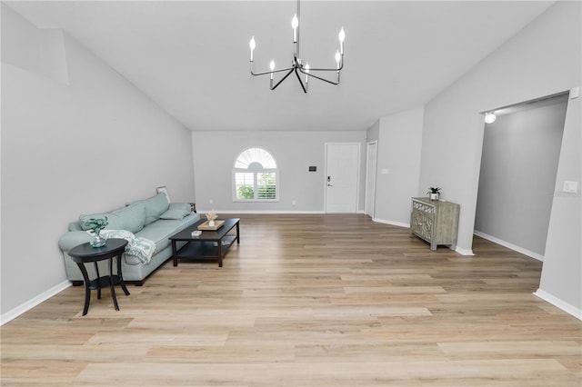 living area with lofted ceiling, an inviting chandelier, baseboards, and wood finished floors