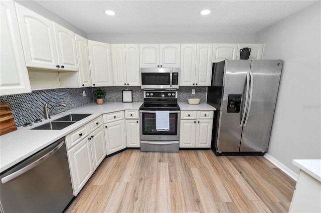 kitchen featuring white cabinets, light wood-style flooring, stainless steel appliances, and a sink