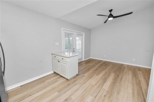 spare room featuring a ceiling fan, baseboards, and light wood finished floors