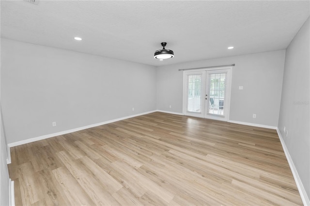 unfurnished room featuring baseboards, a textured ceiling, french doors, light wood-style floors, and recessed lighting