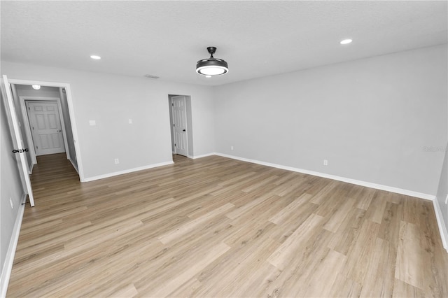 unfurnished room featuring a textured ceiling, recessed lighting, visible vents, baseboards, and light wood finished floors