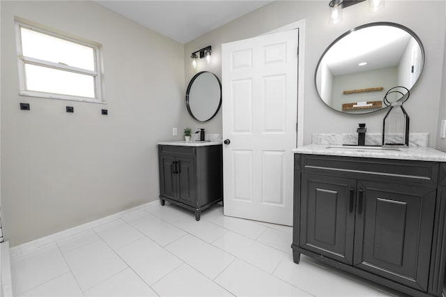 bathroom featuring two vanities, a sink, and baseboards