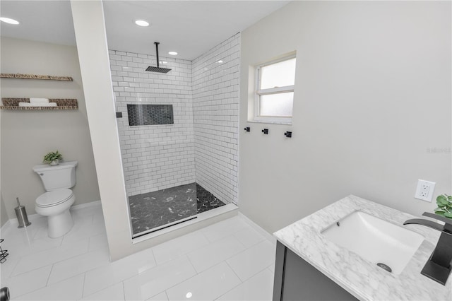 bathroom featuring baseboards, a tile shower, vanity, and toilet