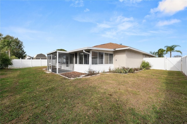 back of property with a yard, stucco siding, a sunroom, a gate, and a fenced backyard