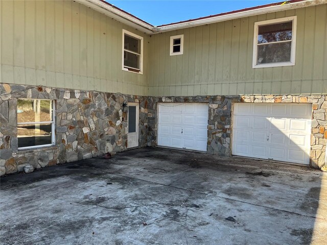 330 Callitris Ave, Polk City, FL 33868 - view of property exterior with stone siding, an attached garage, and concrete driveway