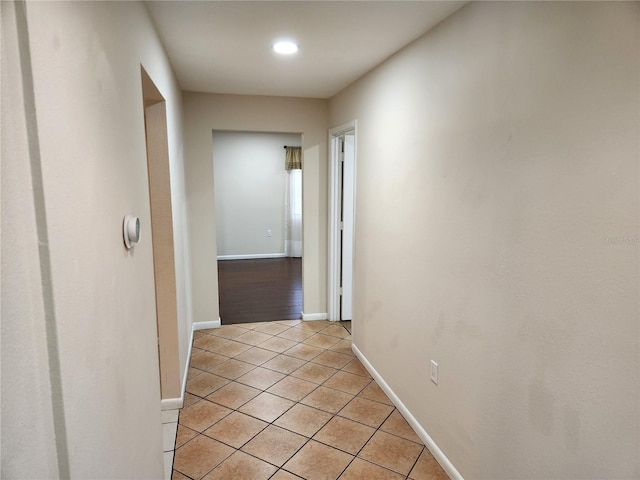 hall with light tile patterned flooring and baseboards