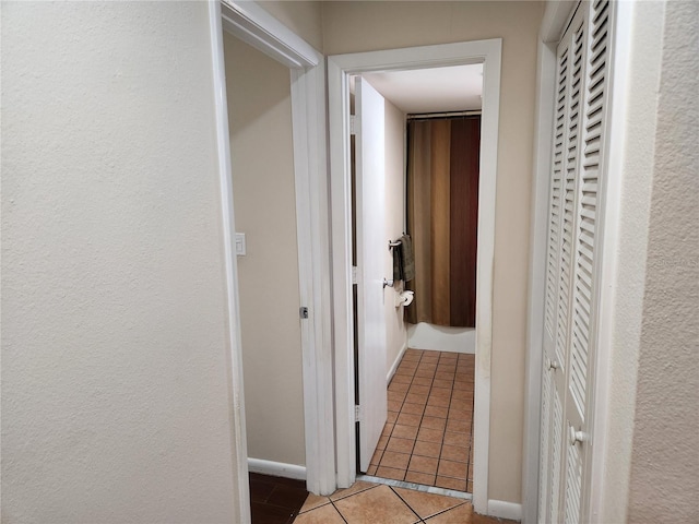 corridor featuring tile patterned flooring and baseboards