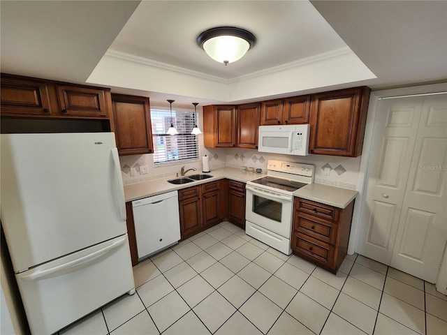 kitchen featuring light countertops, hanging light fixtures, backsplash, a sink, and white appliances