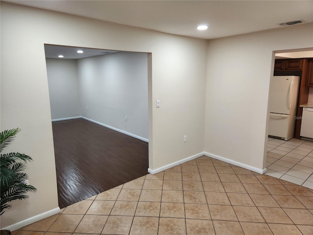 empty room with light tile patterned flooring, visible vents, and baseboards