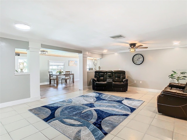 tiled living room featuring baseboards, visible vents, a ceiling fan, and ornate columns