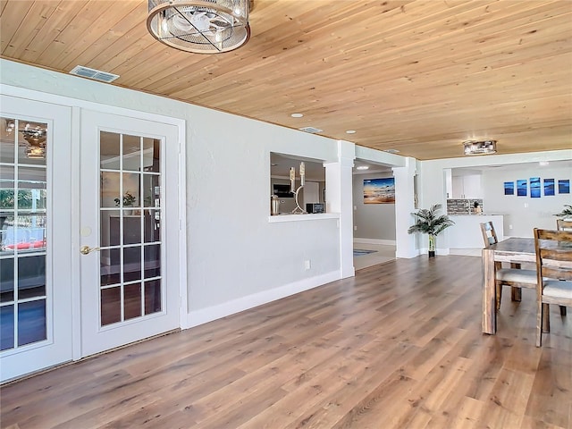 unfurnished dining area with wood finished floors, visible vents, wood ceiling, baseboards, and french doors