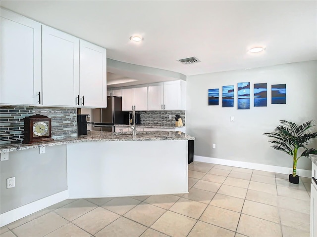 kitchen with light tile patterned floors, visible vents, a peninsula, stone counters, and white cabinetry