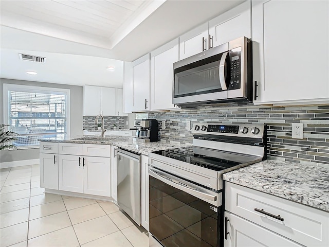 kitchen with light tile patterned floors, stainless steel appliances, a sink, visible vents, and decorative backsplash