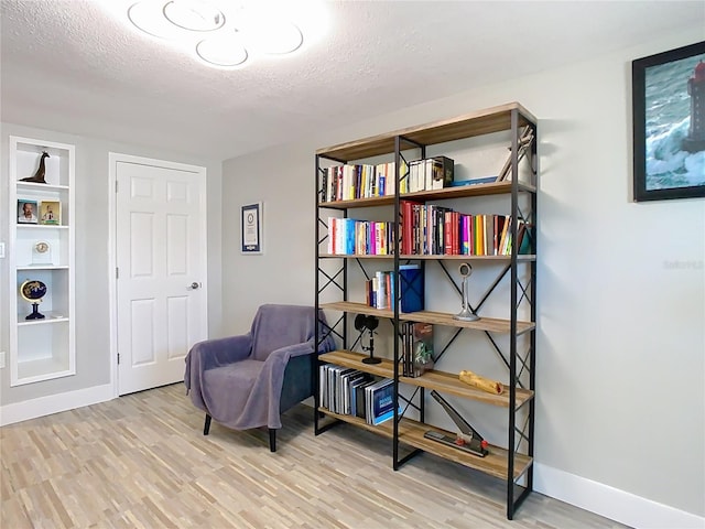 sitting room featuring a textured ceiling, baseboards, and light wood-style floors