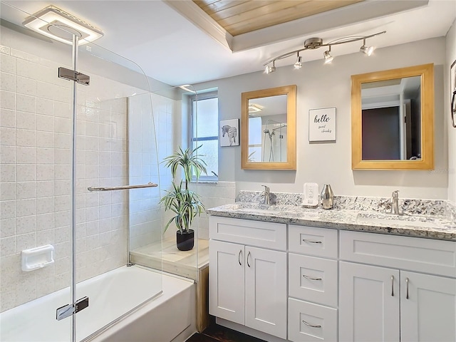 bathroom featuring double vanity, bath / shower combo with glass door, and a sink