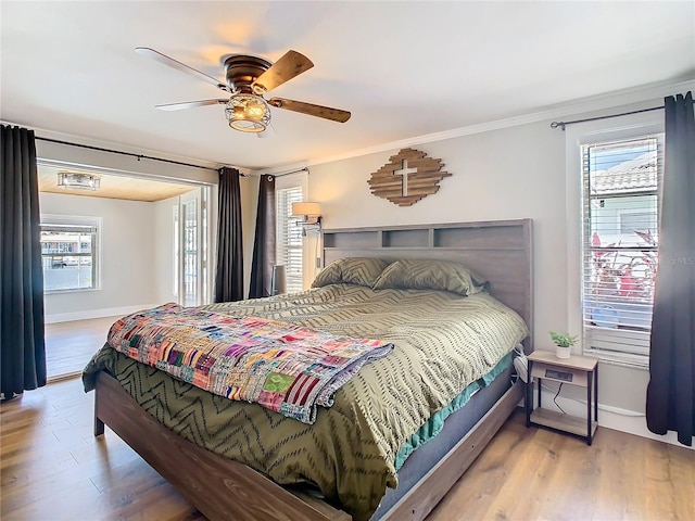 bedroom featuring a ceiling fan, crown molding, baseboards, and wood finished floors