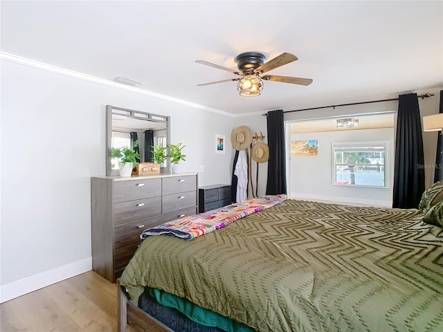 bedroom with visible vents, baseboards, a ceiling fan, crown molding, and light wood-type flooring