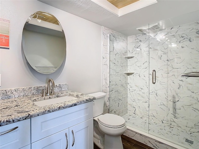 bathroom with toilet, a shower stall, wood finished floors, and vanity