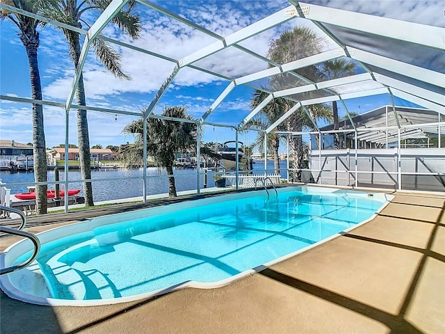 pool featuring glass enclosure, a patio, and a water view