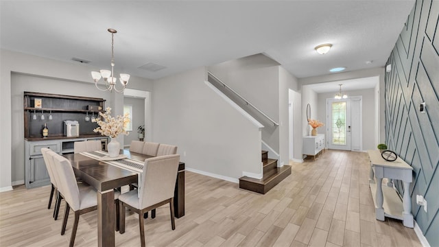 dining room featuring a notable chandelier, visible vents, light wood-style floors, baseboards, and stairs