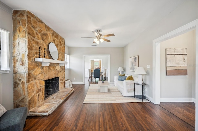 living area featuring a fireplace, visible vents, a ceiling fan, wood finished floors, and baseboards