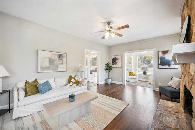 living area featuring baseboards, a ceiling fan, and wood finished floors