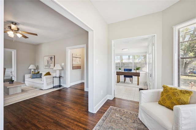 sitting room with baseboards, ceiling fan, dark wood finished floors, and a healthy amount of sunlight