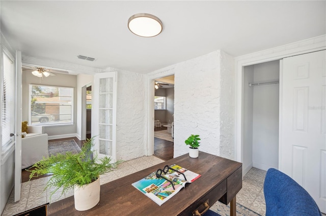 home office with ceiling fan, a textured wall, and visible vents