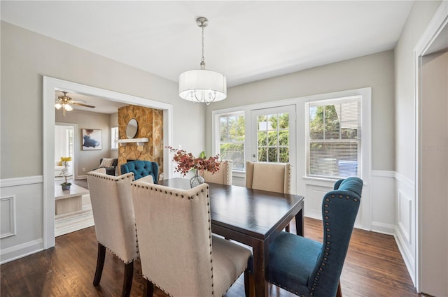 dining area with dark wood-style floors, wainscoting, and a decorative wall