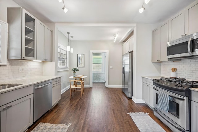 kitchen with stainless steel appliances, dark wood-type flooring, glass insert cabinets, and light stone countertops