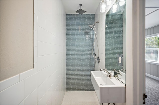 bathroom with a wainscoted wall, tiled shower, and a sink