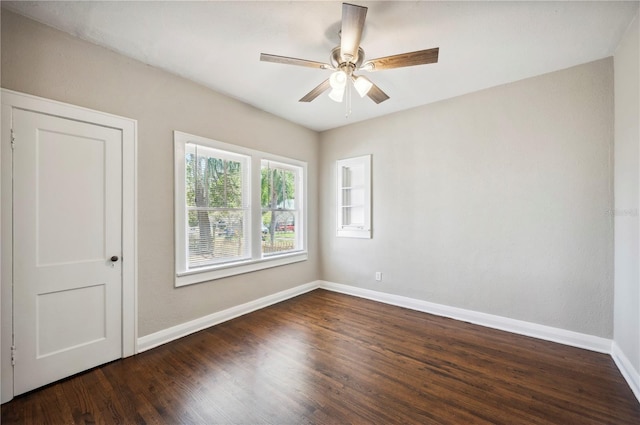 spare room with wood finished floors, a ceiling fan, and baseboards