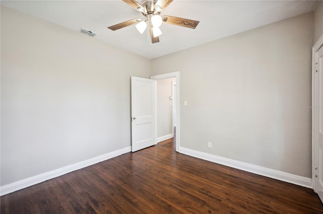 empty room featuring dark wood-type flooring, visible vents, baseboards, and a ceiling fan