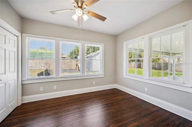 unfurnished room with a ceiling fan, dark wood finished floors, and baseboards