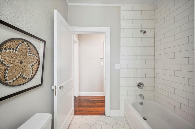 bathroom featuring baseboards, bathing tub / shower combination, toilet, tile patterned floors, and crown molding