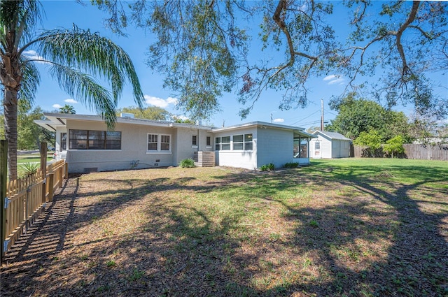 rear view of house with an outbuilding, crawl space, a fenced backyard, and a lawn