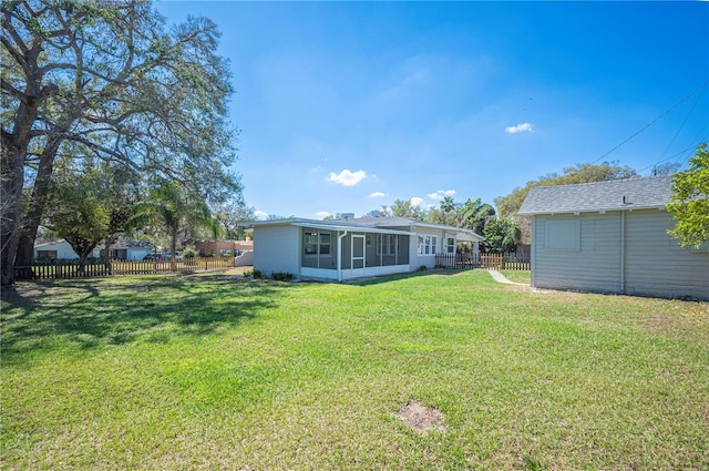 rear view of property featuring fence private yard, a sunroom, a lawn, and an outdoor structure