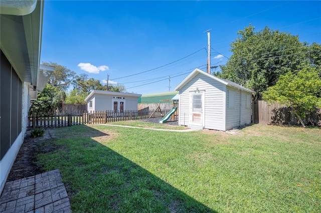 view of yard featuring a fenced backyard, a playground, and an outdoor structure