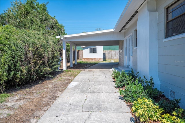 exterior space with fence, a carport, and concrete driveway