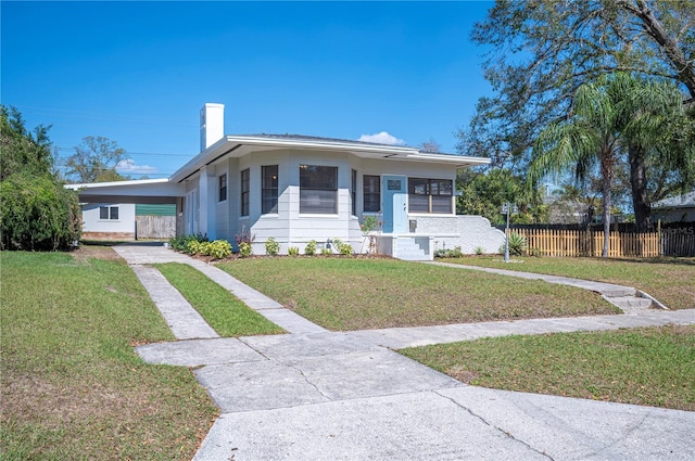 view of front of property with a carport, a front yard, fence, and a chimney