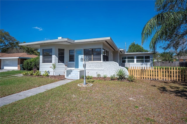 view of front of home featuring a garage, a sunroom, fence, and a front yard