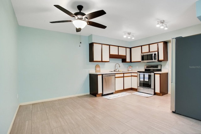 kitchen featuring baseboards, appliances with stainless steel finishes, light countertops, and a sink