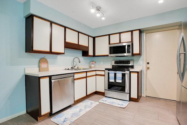 kitchen with baseboards, stainless steel appliances, a sink, and light countertops