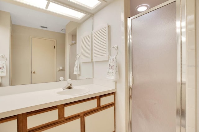 full bath featuring vanity, a skylight, a shower stall, and visible vents