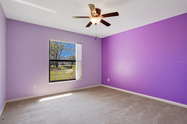 carpeted empty room with ceiling fan and baseboards