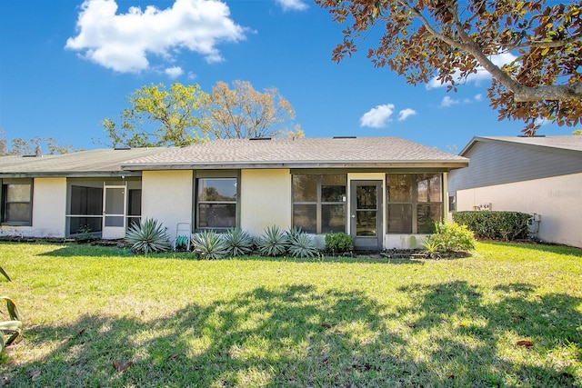 back of property with a yard, a sunroom, and stucco siding