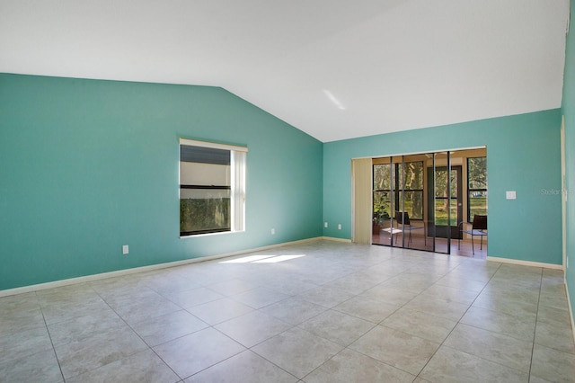 tiled empty room with lofted ceiling and baseboards