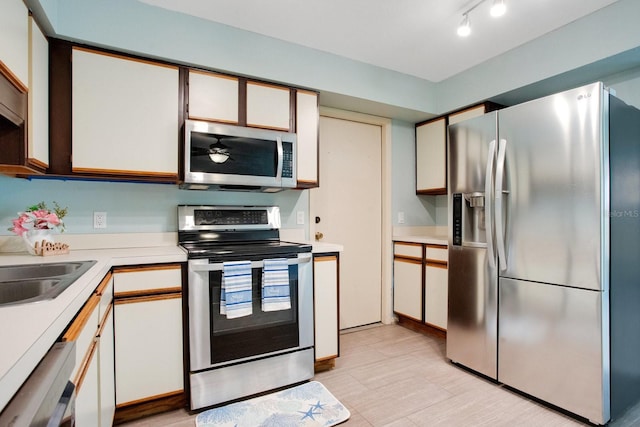 kitchen with a sink, a ceiling fan, light countertops, appliances with stainless steel finishes, and track lighting