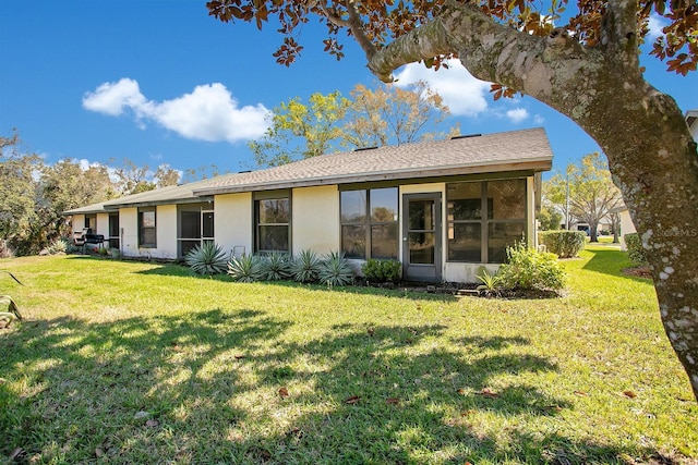 rear view of house with a yard and stucco siding