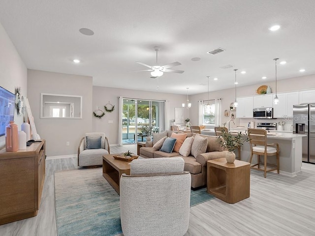 living area with recessed lighting, baseboards, visible vents, and light wood finished floors